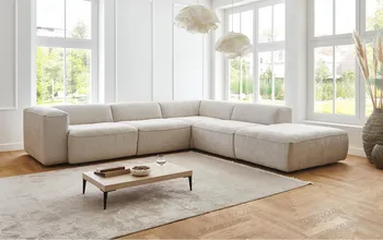 Großes Ecksofa im hellen natur durchleuchteten Raum mit kleinem Couchtisch.